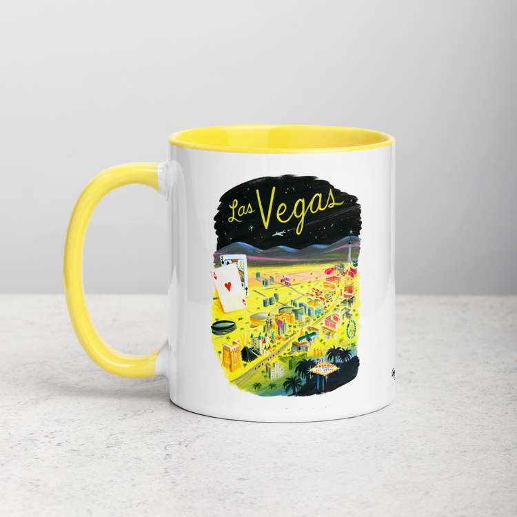 White ceramic coffee mug with yellow handle and inside; has Las Vegas illustration by Angela Staehling