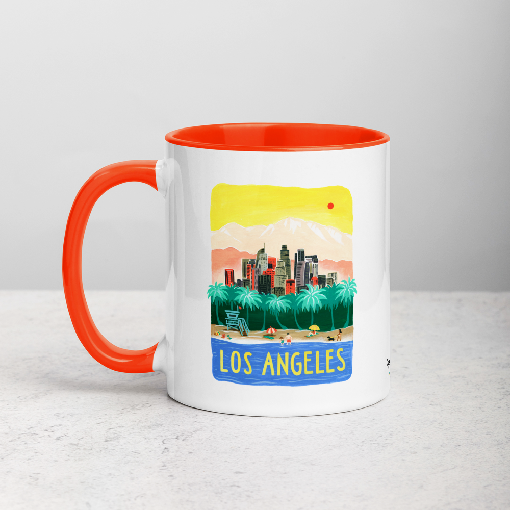 White ceramic coffee mug with orange handle and inside; has Los Angeles California illustration by Angela Staehling