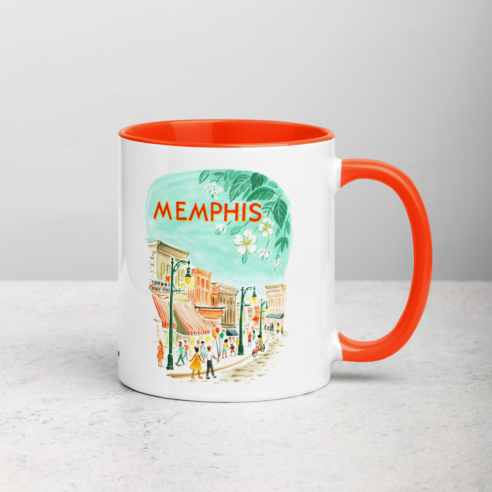 White ceramic coffee mug with orange handle and inside; has Memphis Tennessee illustration by Angela Staehling