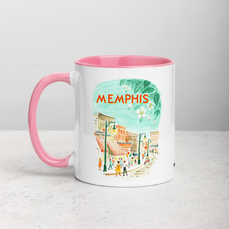 White ceramic coffee mug with pink handle and inside; has Memphis Tennessee illustration by Angela Staehling