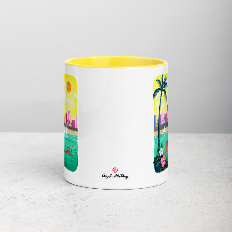White ceramic coffee mug with yellow handle and inside; has Miami Florida illustration by Angela Staehling
