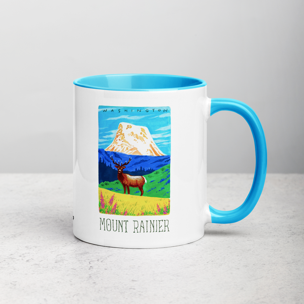White ceramic coffee mug with blue handle and inside; has Mount Rainier National Park illustration by Angela Staehling