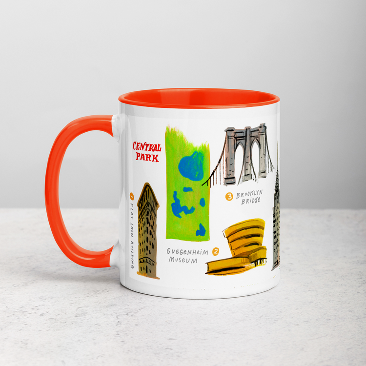 White ceramic coffee mug with orange handle and inside; has New York landmarks illustration by Angela Staehling