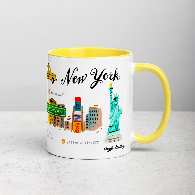 White ceramic coffee mug with yellow handle and inside; has New York landmarks illustration by Angela Staehling