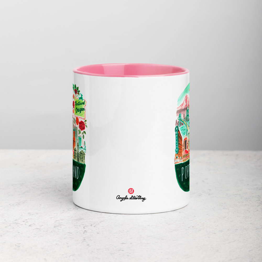White ceramic coffee mug with pink handle and inside; has Portland Oregon illustration by Angela Staehling