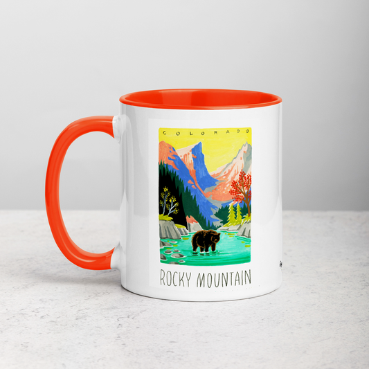White ceramic coffee mug with orange handle and inside; has Rocky Mountain National Park illustration by Angela Staehling