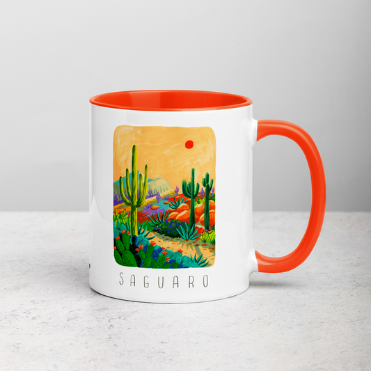 White ceramic coffee mug with orange handle and inside; has Saguaro National Park illustration by Angela Staehling
