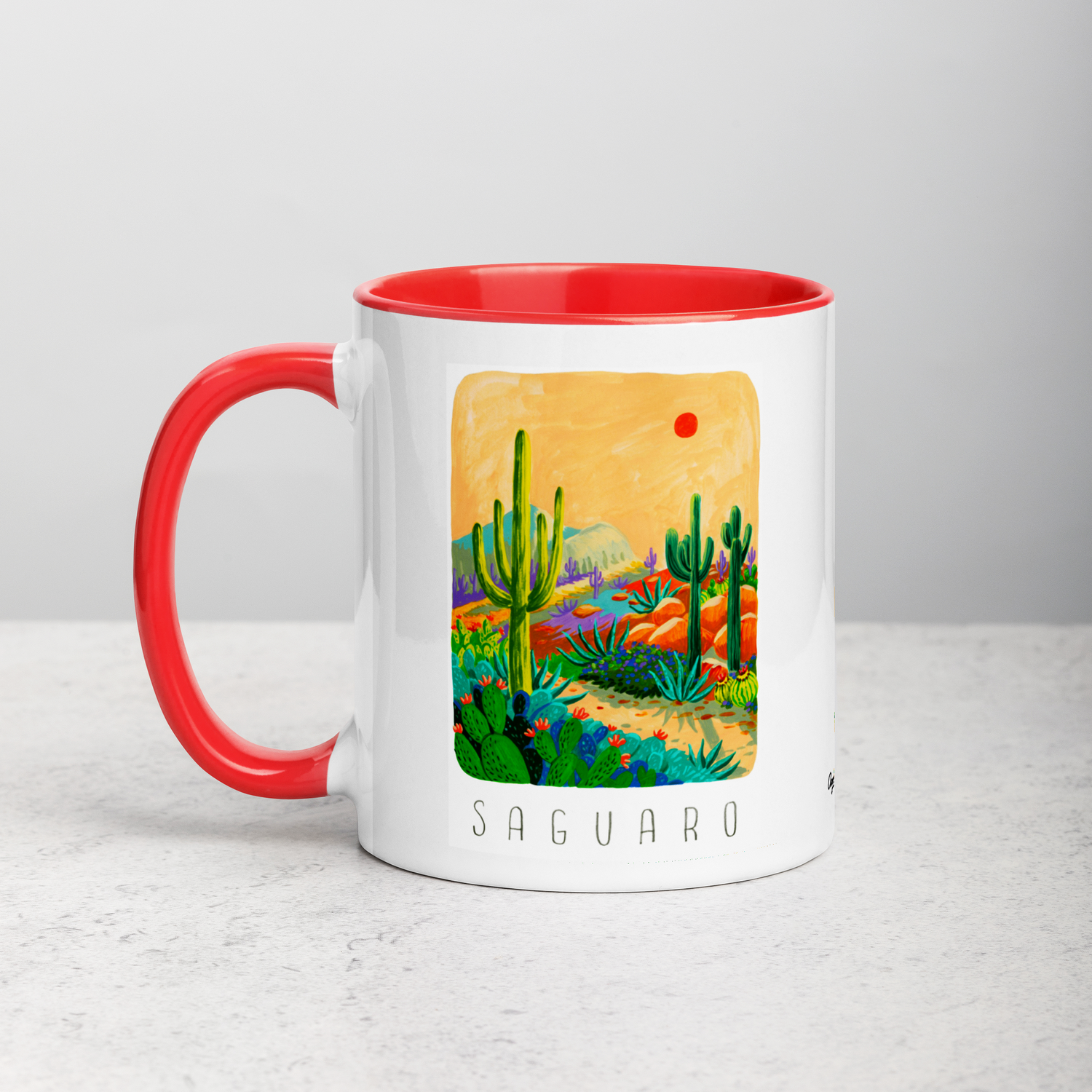 White ceramic coffee mug with red handle and inside; has Saguaro National Park illustration by Angela Staehling