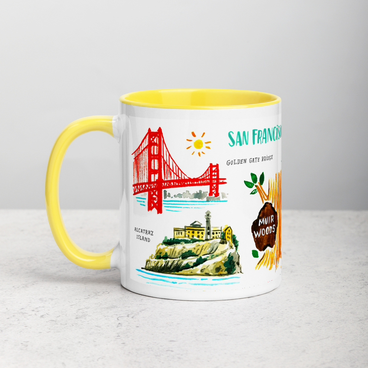 White ceramic coffee mug with yellow handle and inside; has San Francisco landmarks illustration by Angela Staehling