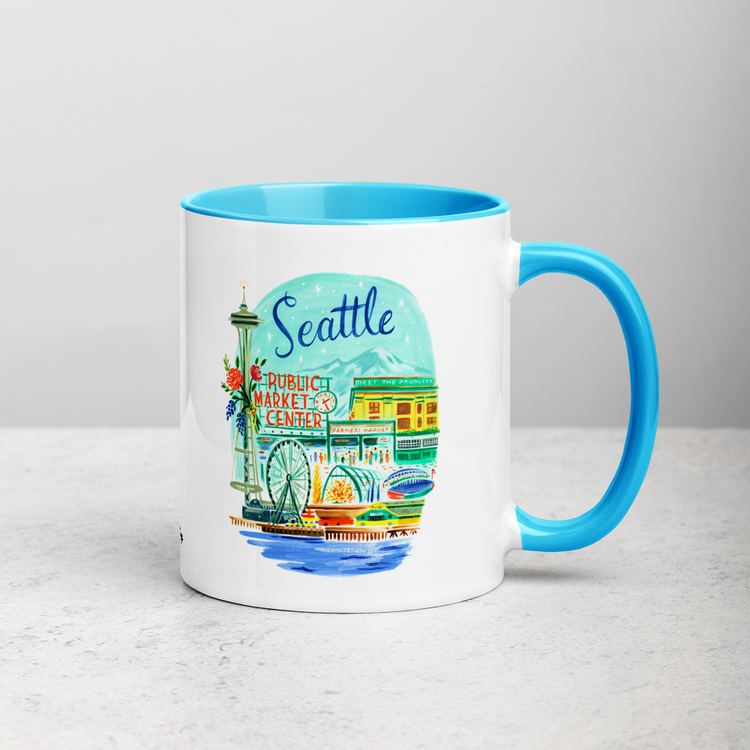 White ceramic coffee mug with blue handle and inside; has Seattle Washington illustration by Angela Staehling