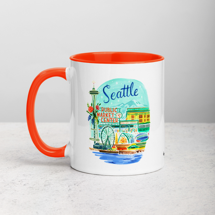 White ceramic coffee mug with orange handle and inside; has Seattle Washington illustration by Angela Staehling