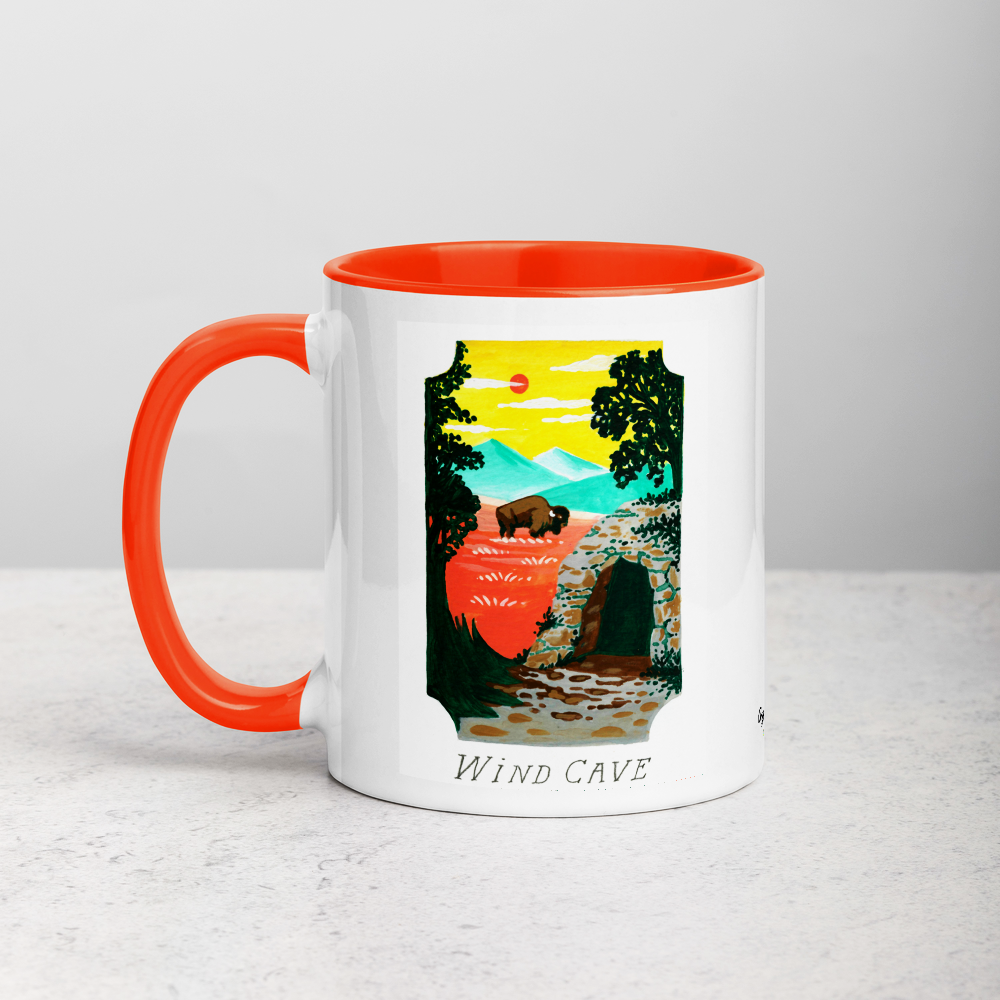 White ceramic coffee mug with orange handle and inside; has Wind Cave National Park illustration by Angela Staehling