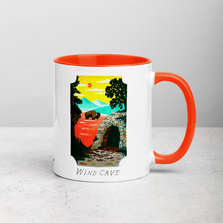 White ceramic coffee mug with orange handle and inside; has Wind Cave National Park illustration by Angela Staehling