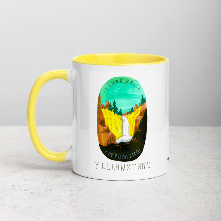 White ceramic coffee mug with yellow handle and inside; has Yellowstone National Park illustration by Angela Staehling