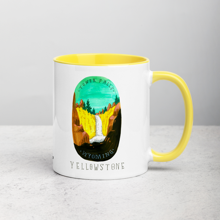 White ceramic coffee mug with yellow handle and inside; has Yellowstone National Park illustration by Angela Staehling