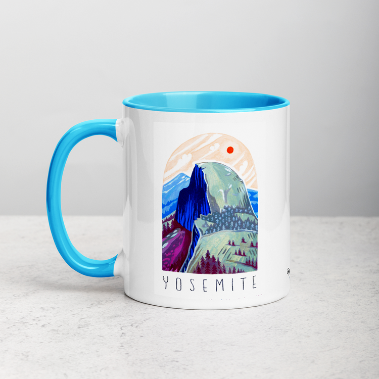 White ceramic coffee mug with blue handle and inside; has Yosemite National Park illustration by Angela Staehling