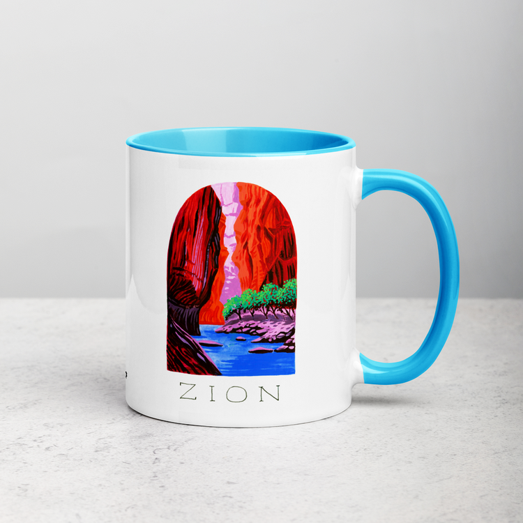 White ceramic coffee mug with blue handle and inside; has Zion National Park illustration by Angela Staehling